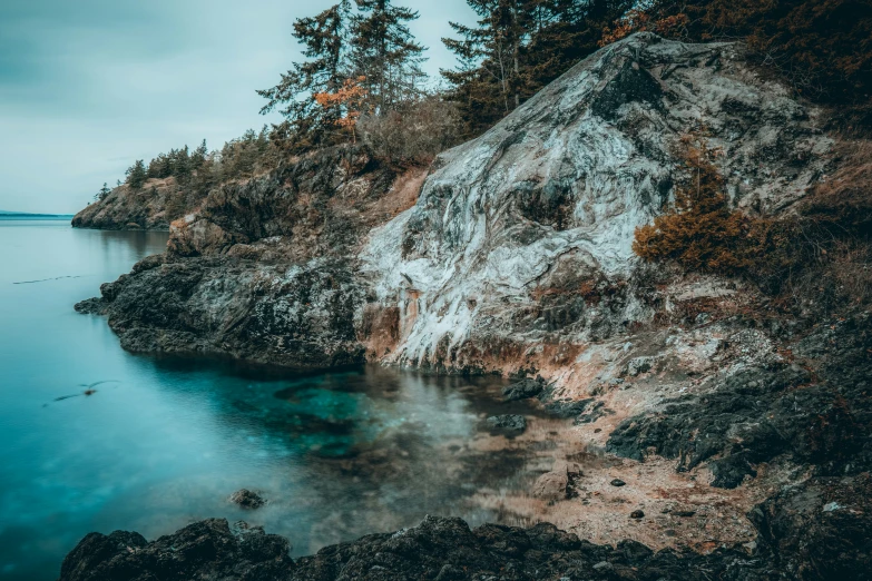 an island with trees and rocks sitting next to the ocean