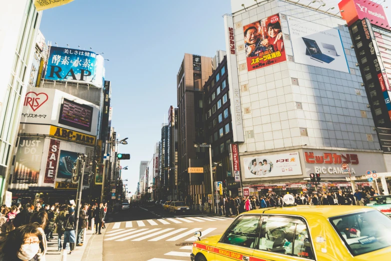 a yellow taxi driving down a street near tall buildings