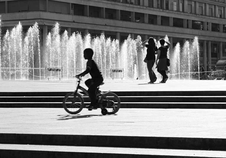 a  riding a bike in front of a water fountain