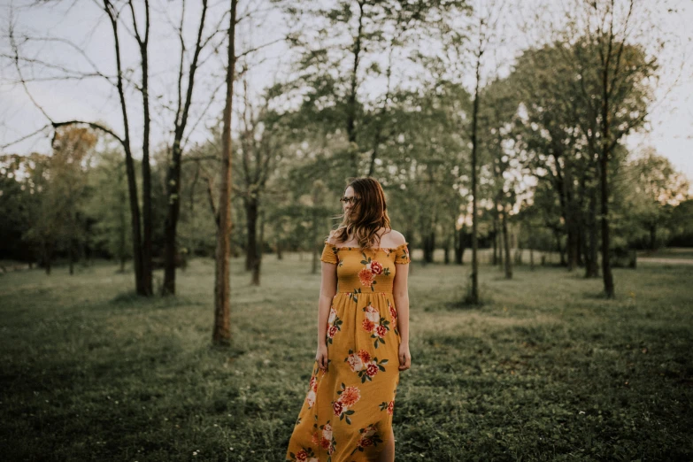 a woman in a long yellow dress walking in the grass