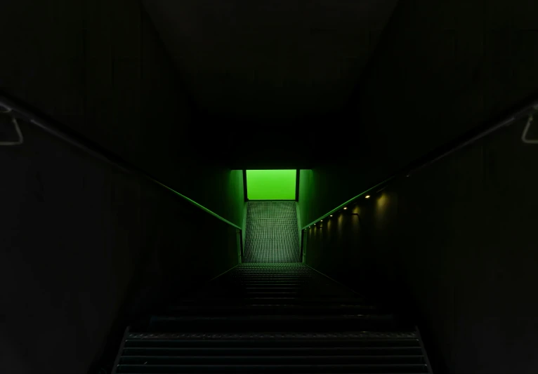 a stairwell leading to a small door with green light