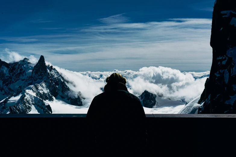 a person sitting on a bench looking over the snow