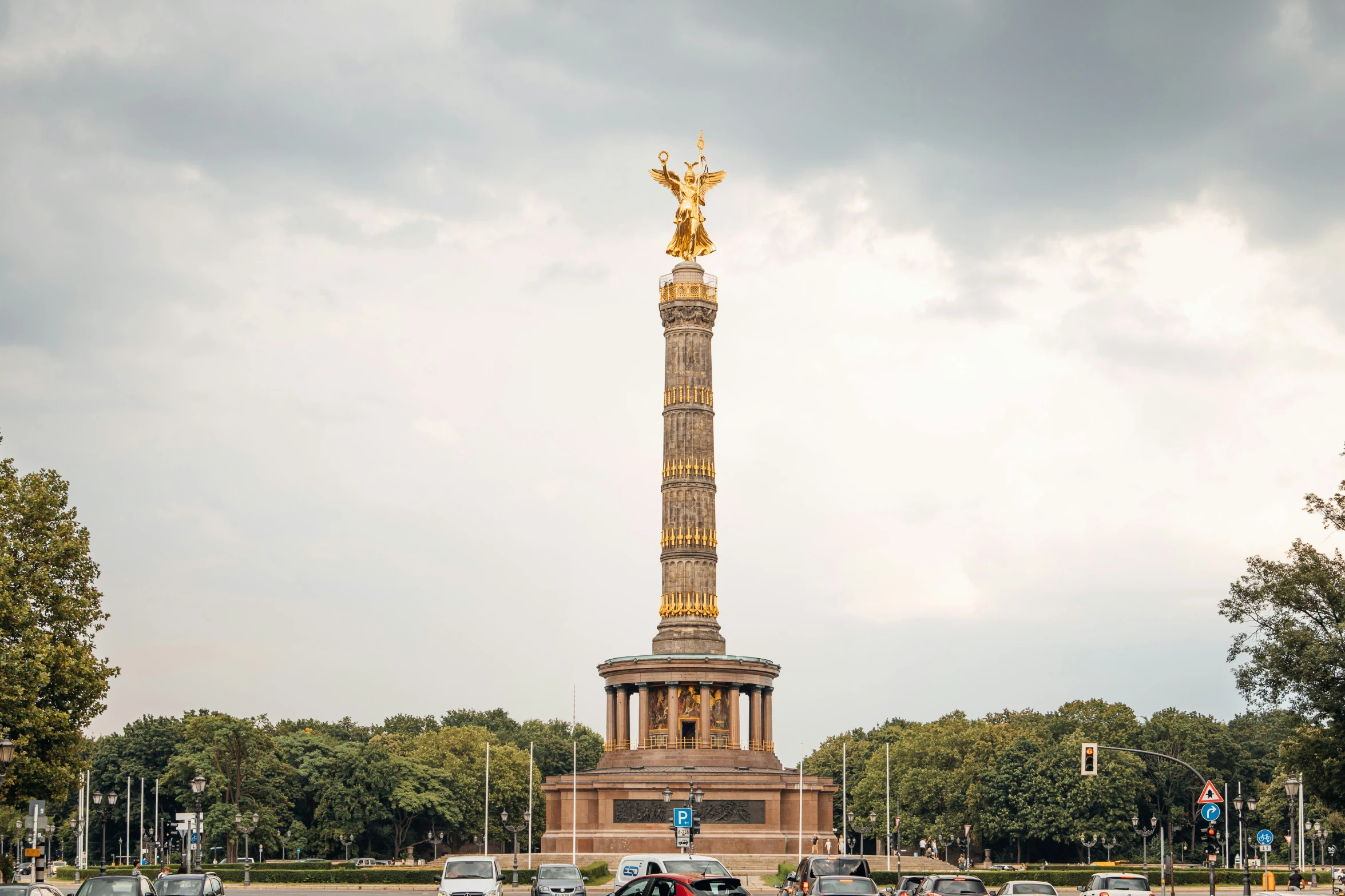 a traffic light sitting below a tall gold statue