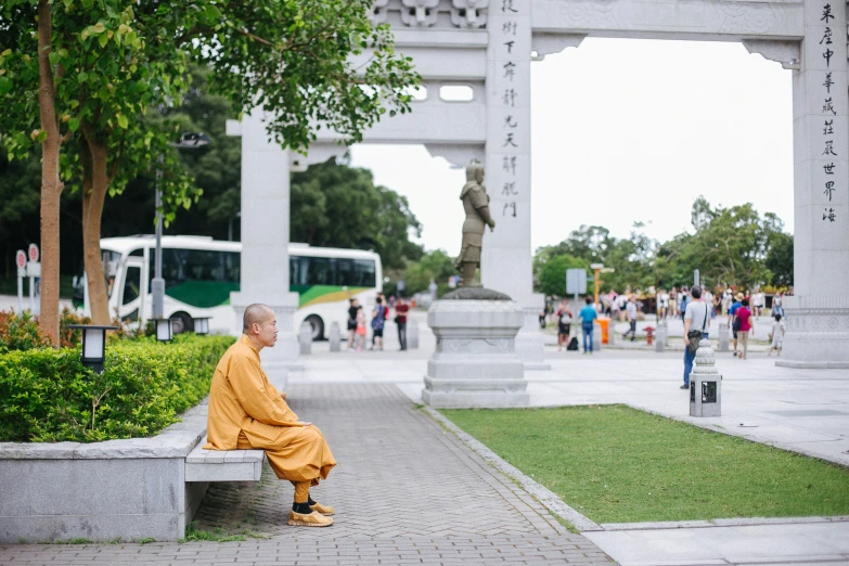 a man in a yellow robe is sitting on a bench