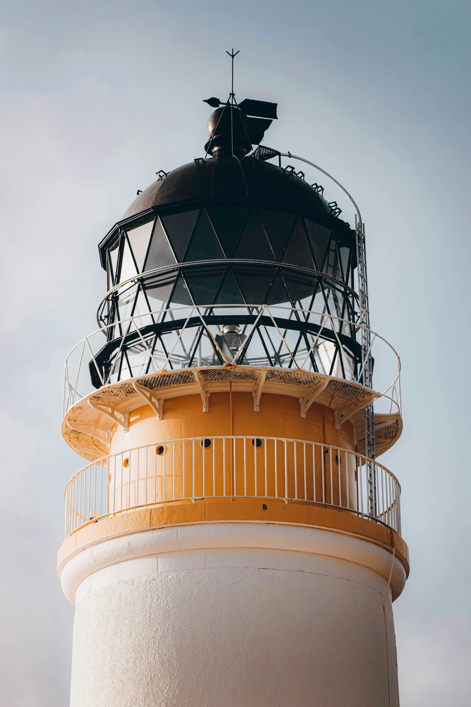 a large white and yellow lighthouse under a blue sky