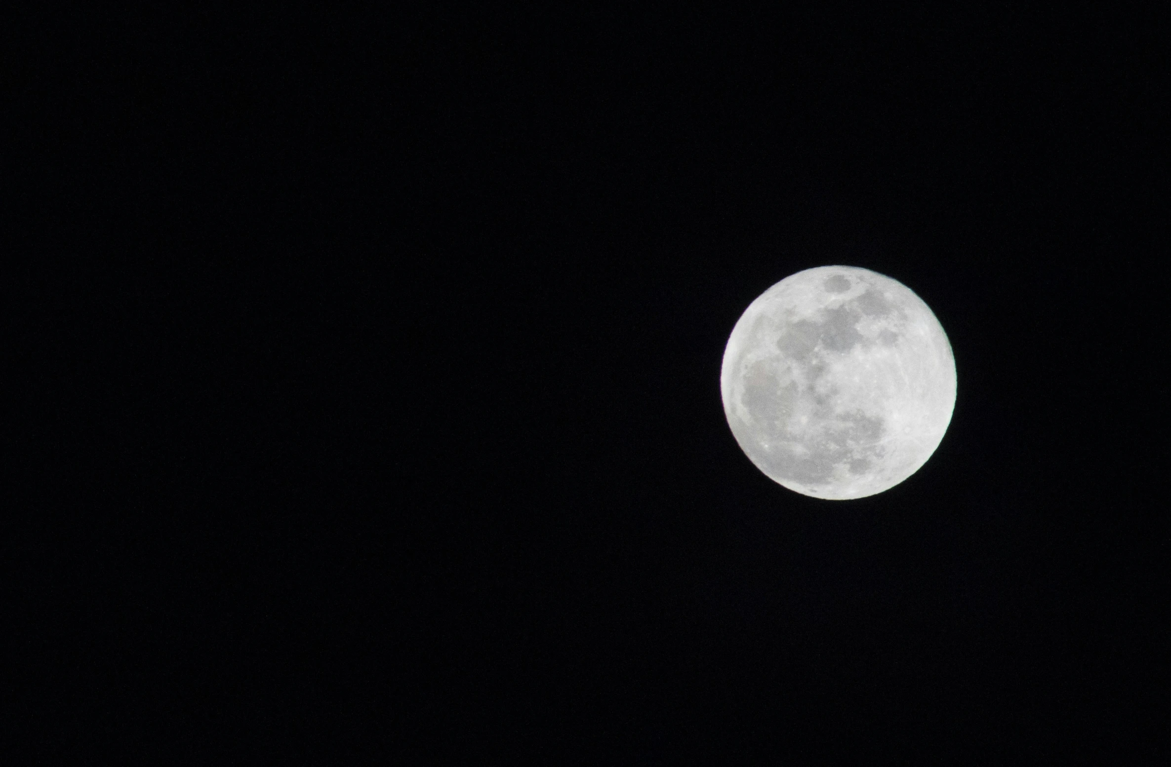 a plane flying by a large full moon in the sky