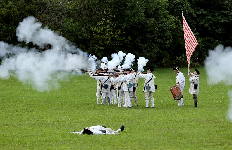 a group of people in uniforms with flags and smoke on a grassy field