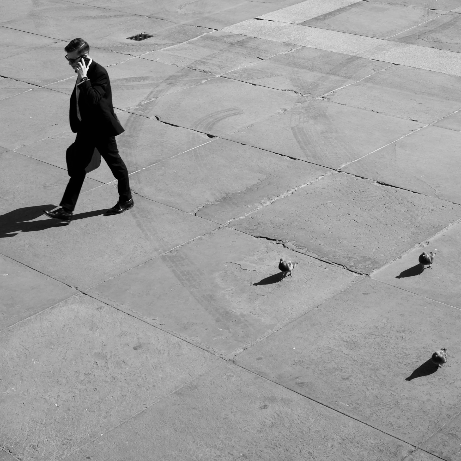 a man with black tie and suit walking across a stone floor