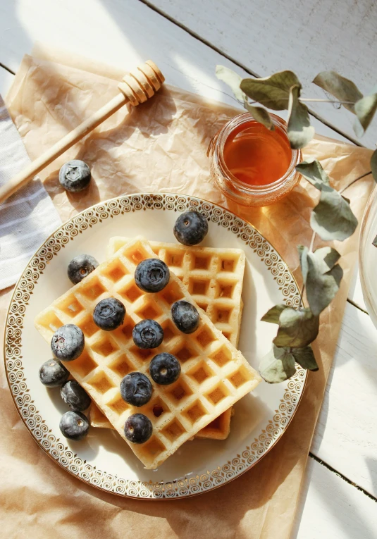 a plate topped with waffles next to a cup of syrup