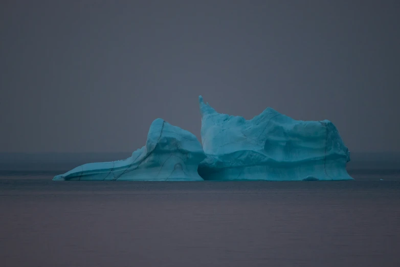 a large blue iceberg in the ocean on a foggy day