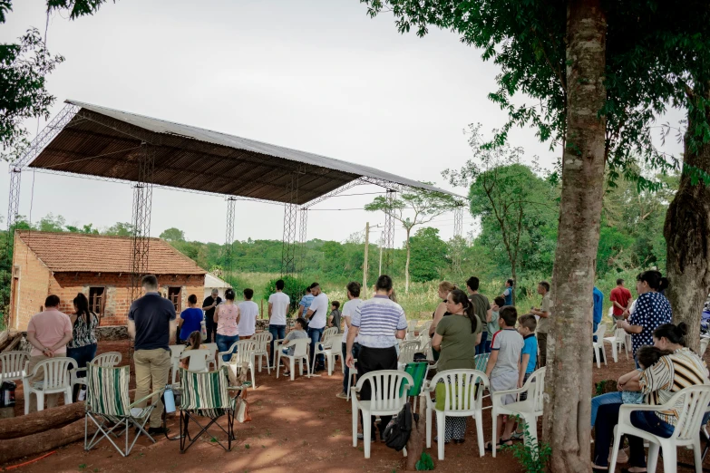 people sitting in chairs under a tent on a field