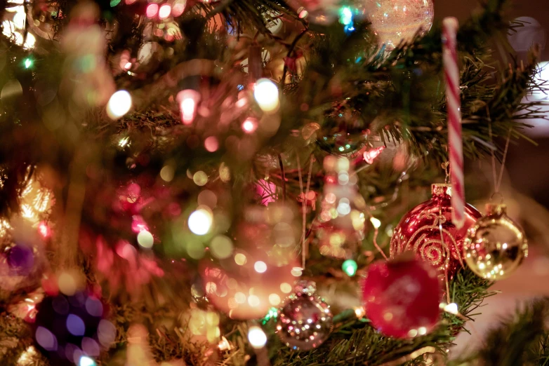 a christmas tree is decorated with multi - colored ornaments