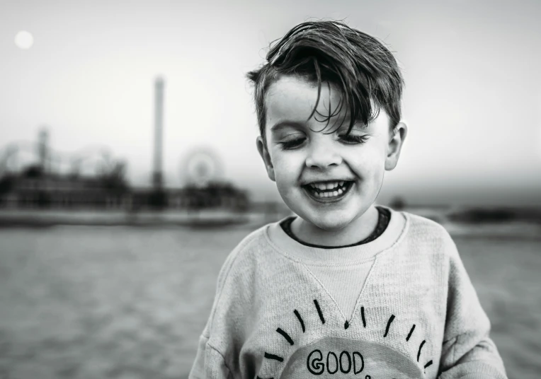 the little boy smiles at the camera while holding his hands in his pockets