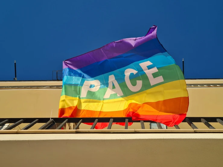 a rainbow flag waving in the wind with peace on it