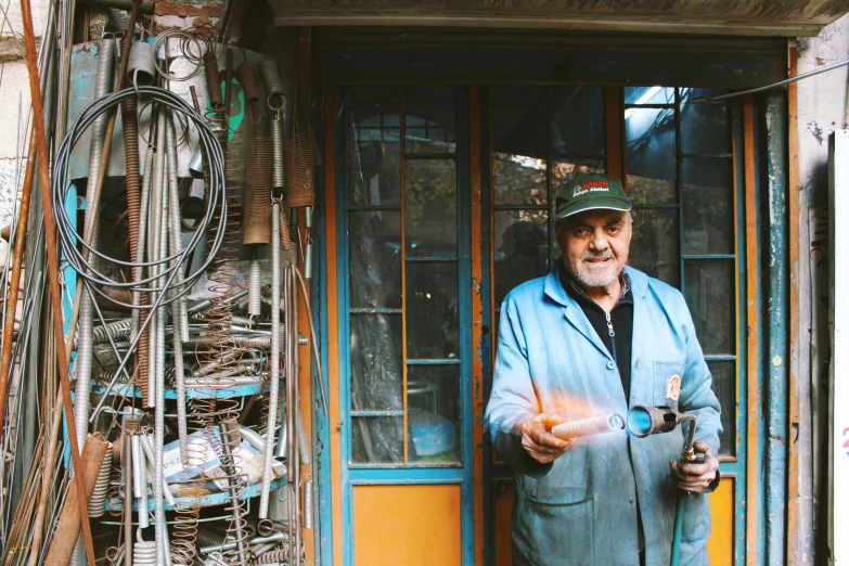 a man holding a glass in front of a door with wires everywhere