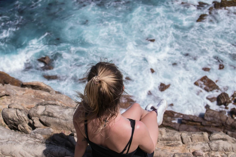 a woman is looking out at the ocean from above