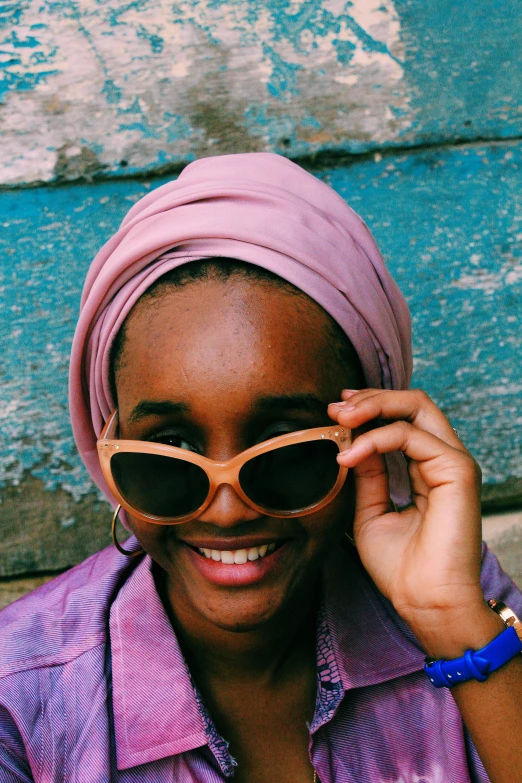 a woman smiles as she holds up her sunglasses