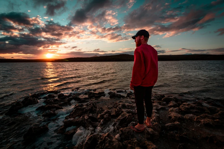 man on rocks standing in front of a body of water