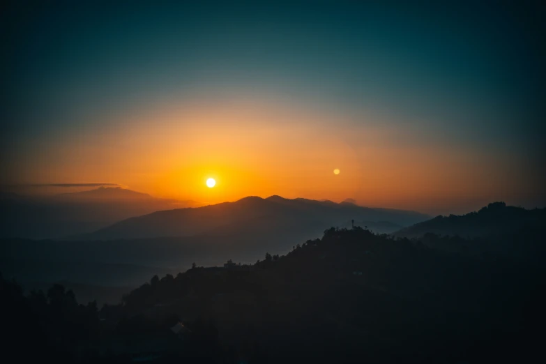 a picture of the sun going down behind a mountain