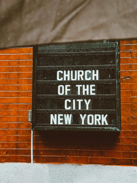 a church sign mounted to a brick wall