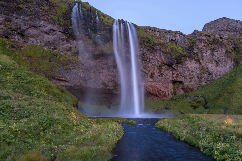 a very tall waterfall next to a blue river