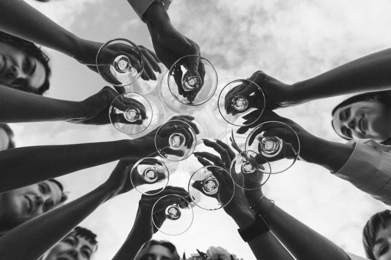 several people holding glasses with hands together