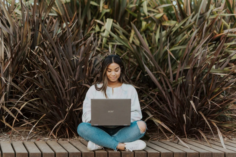 woman sitting on bricks outside and working on a laptop