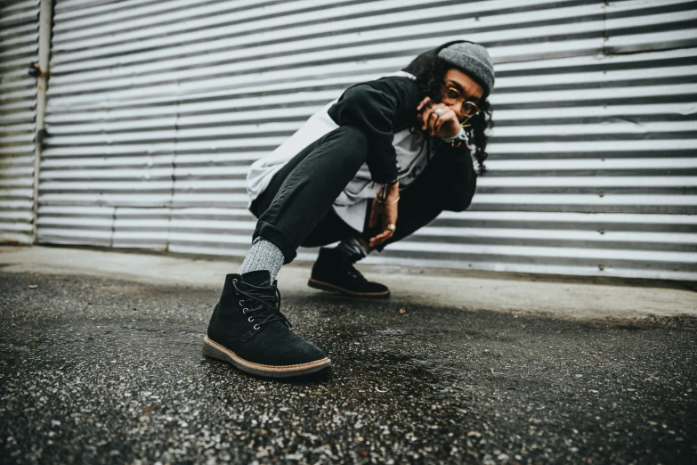 the boy poses on the side of the building with his feet in the air