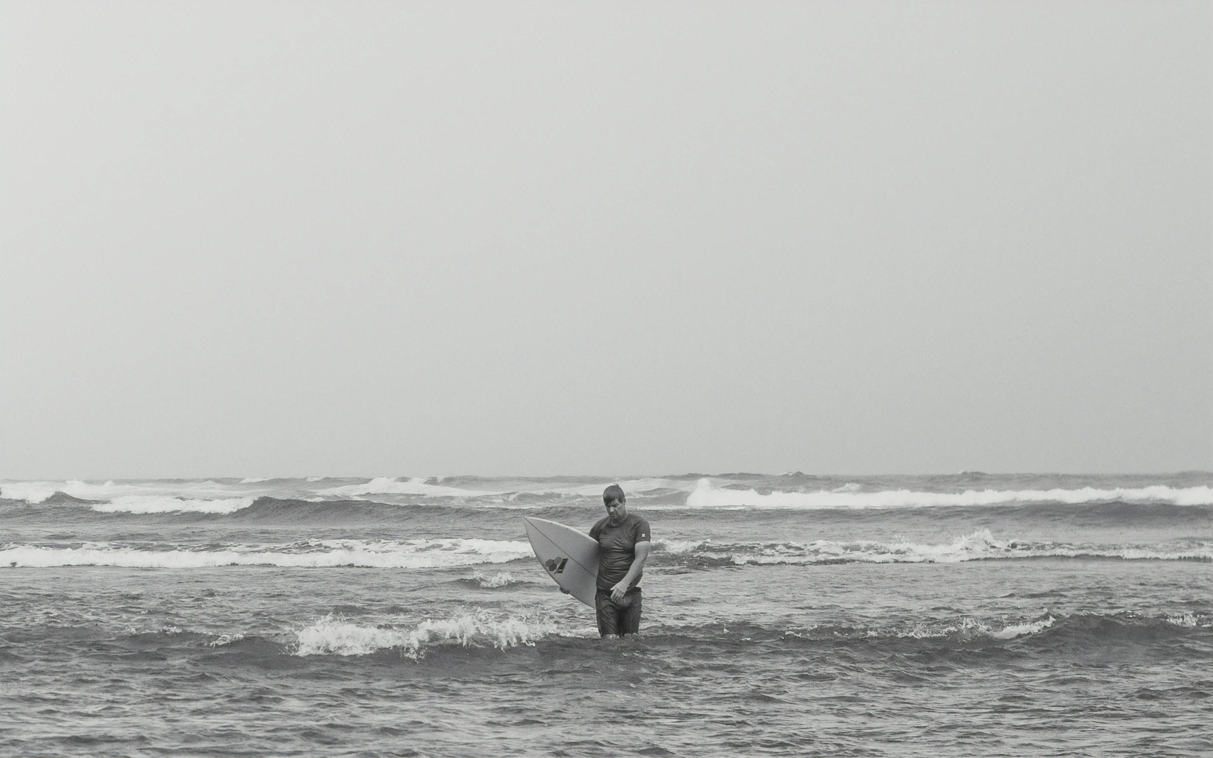 a surfer walking into the ocean carrying his board