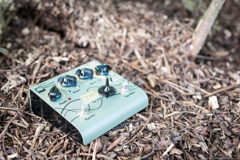 an image of a green frissbee pedalbox sitting in the woods