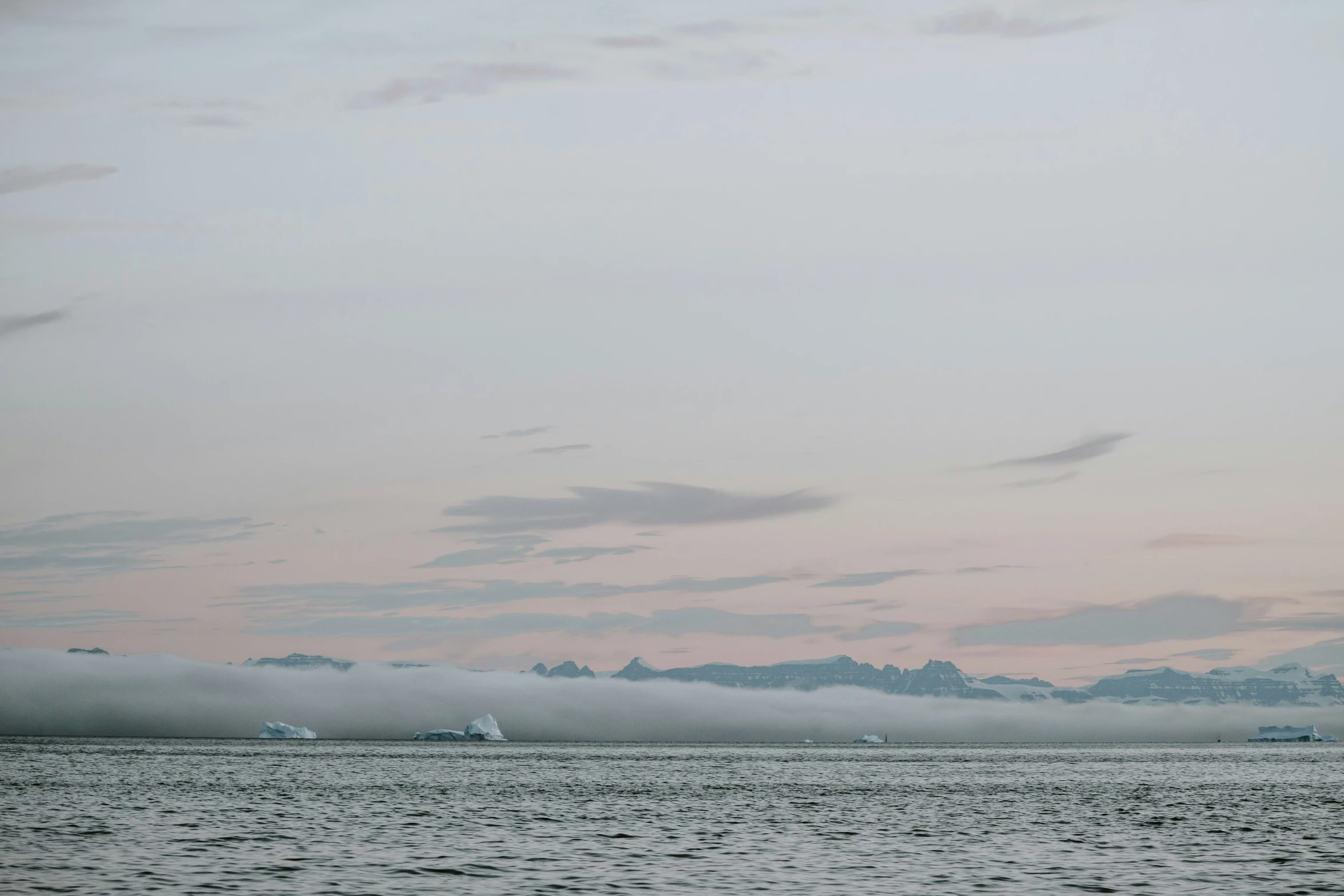 a large body of water under a pink sky