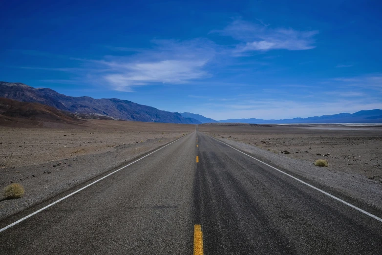 a lone yellow sign is in the middle of an empty highway