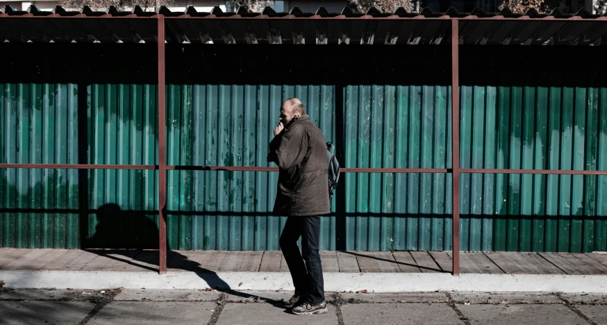 a man is walking down the street, talking on his cellphone