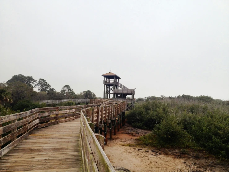 a wooden bridge stretches over a sandy coastline and onto the ocean