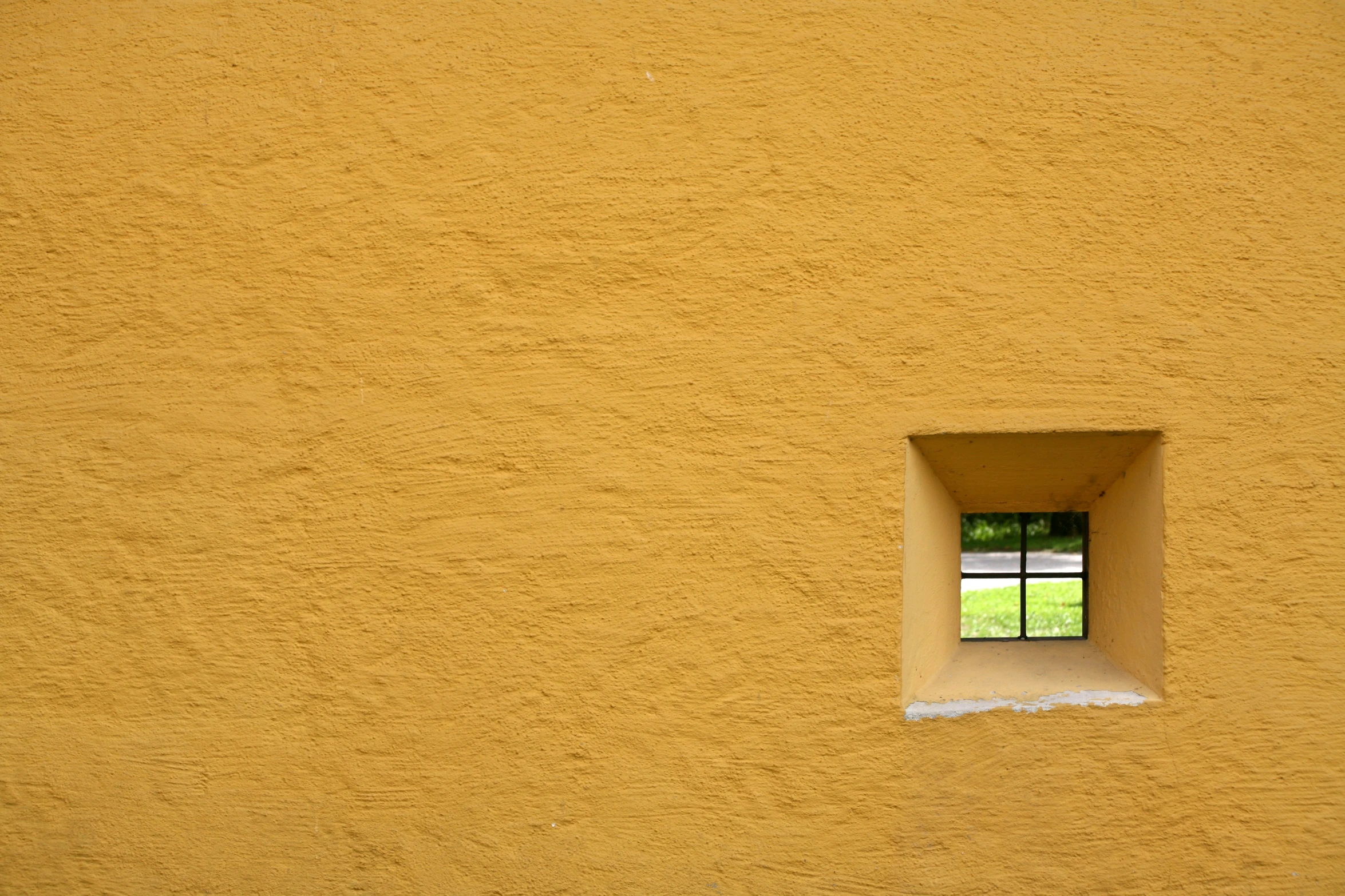 the view from the outside of an orange wall with a window