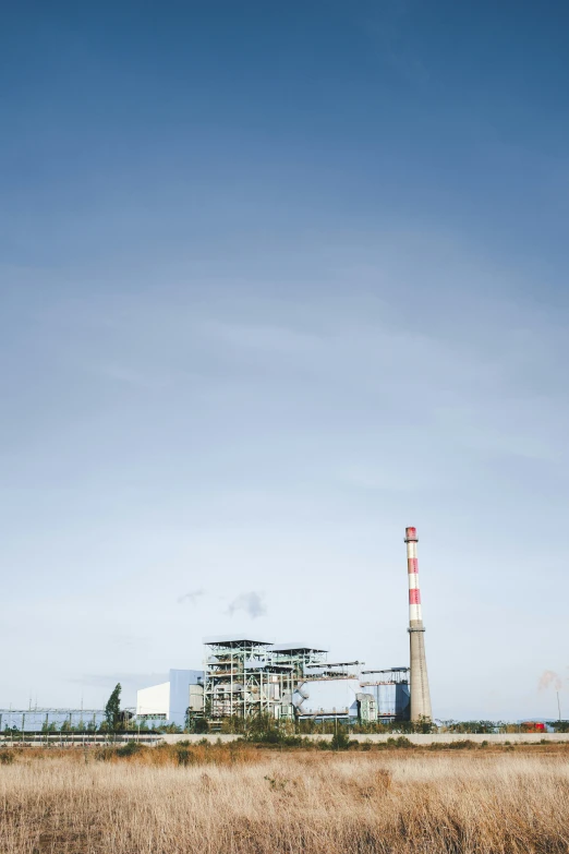 an industrial factory in an empty field with grass