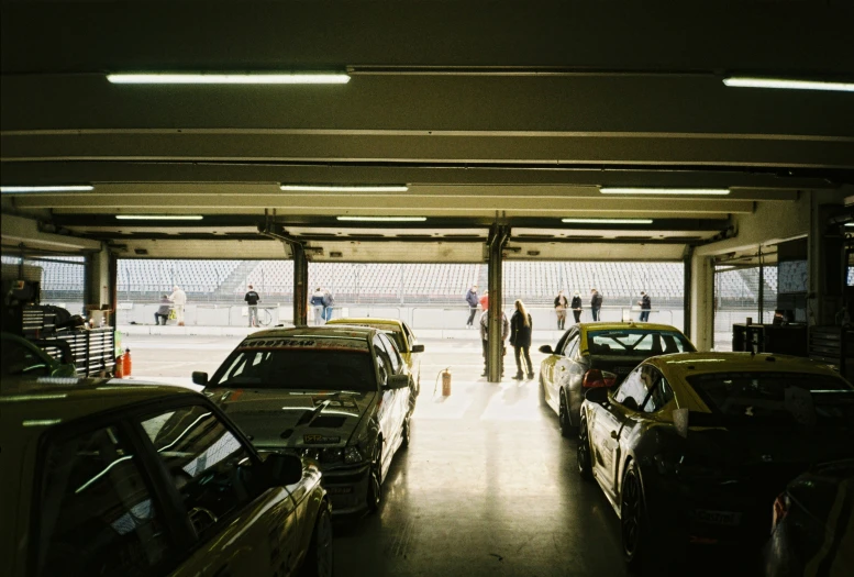 several cars in a garage with people in the background