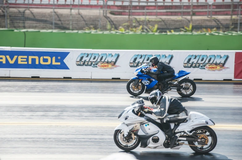 three motorcyclists performing tricks on motorcycles around the track