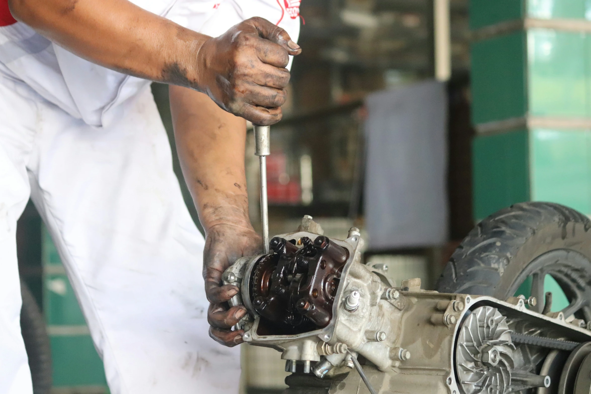 the man in the white uniform works on a small engine