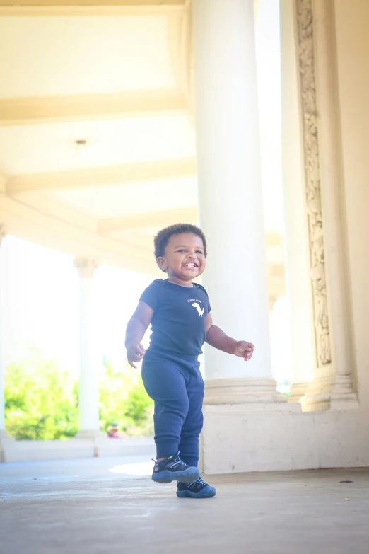 a small child running in the sun near a building