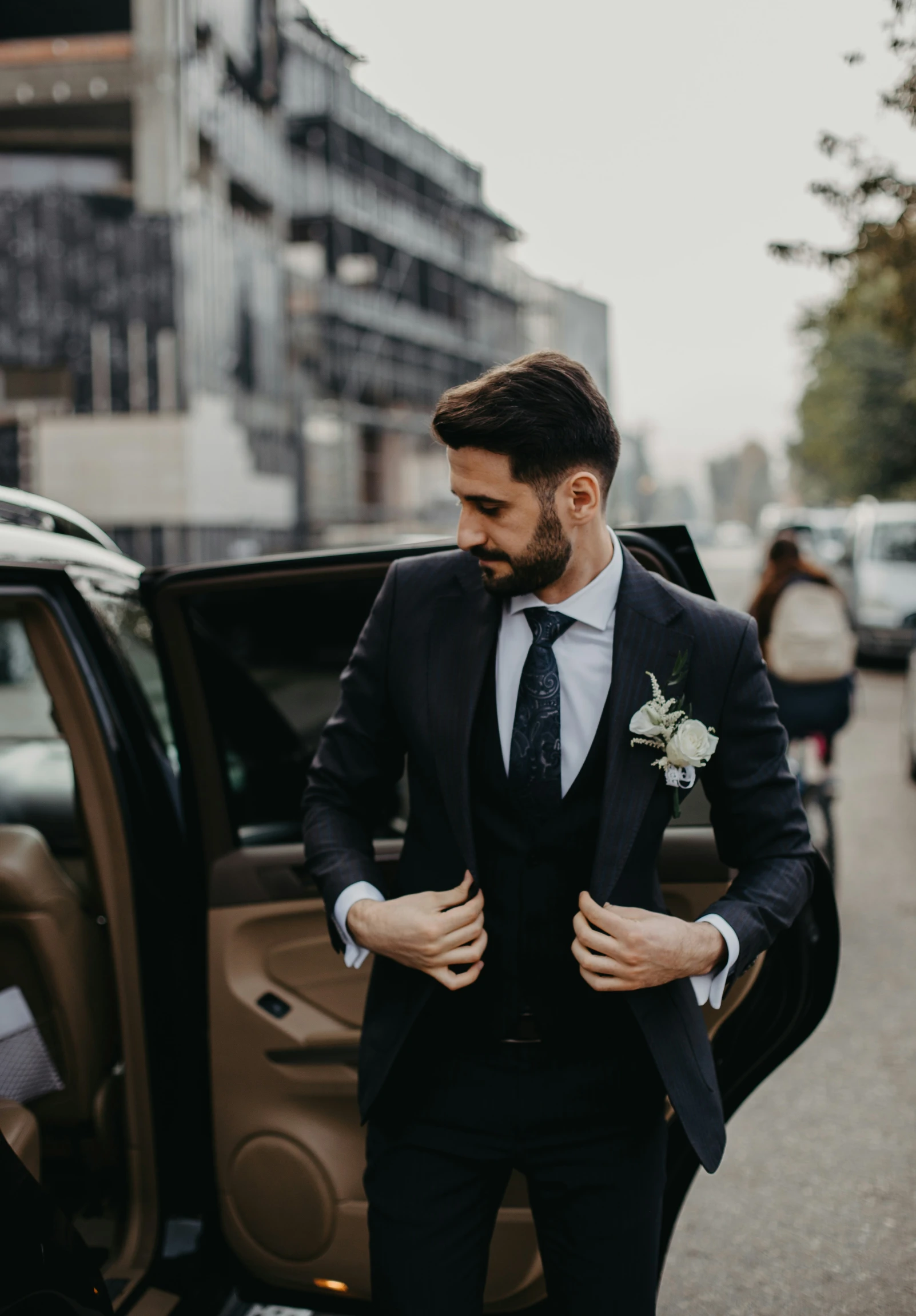 a man in a black suit is getting out of a car