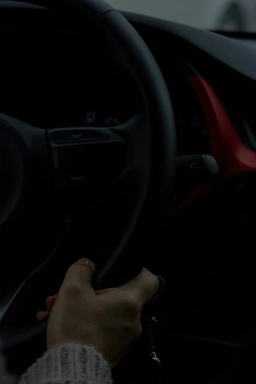 a person holding the steering wheel of a car in the dark