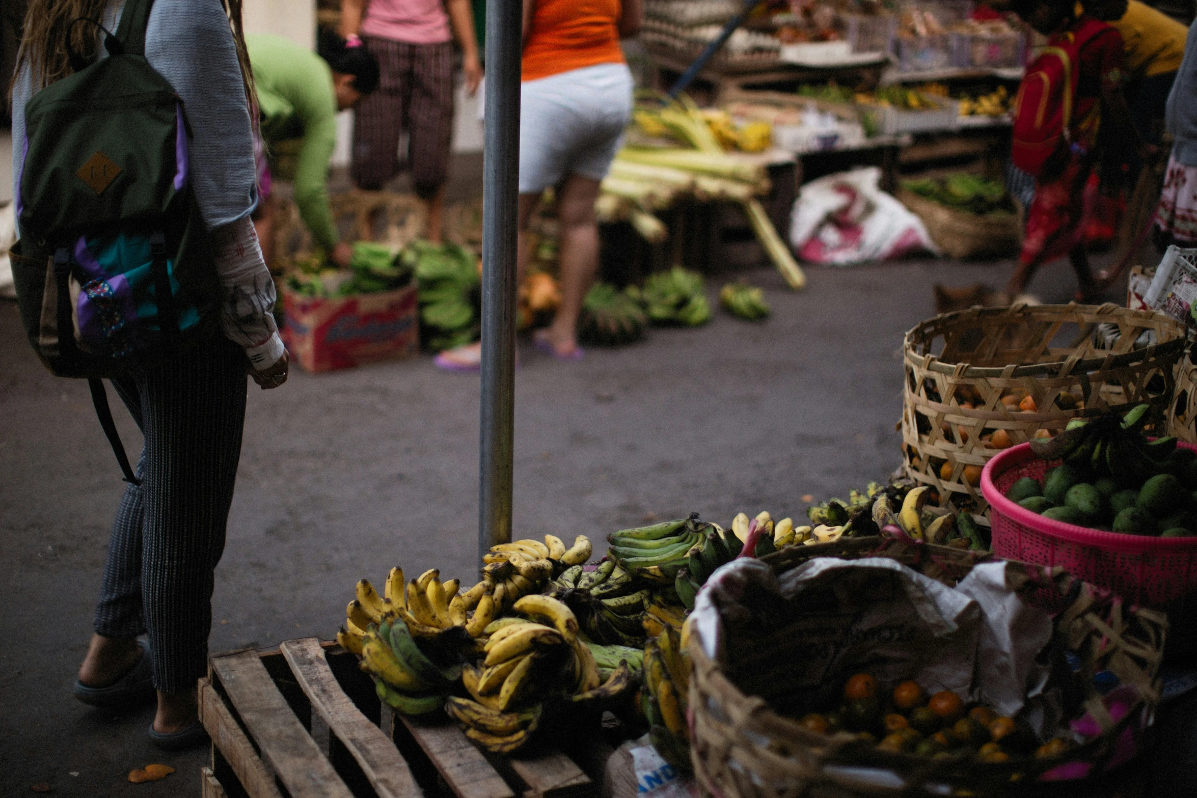 the woman walks past an outside fruit stand