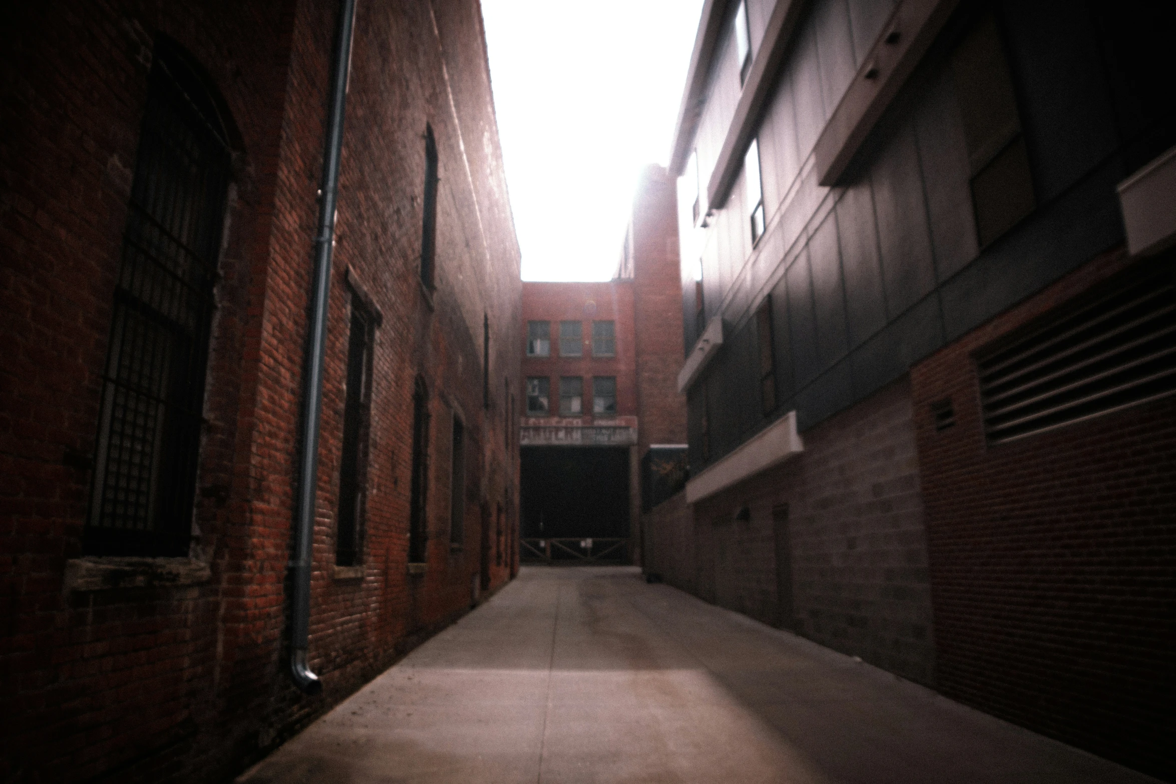an empty alley with brick buildings and a small building