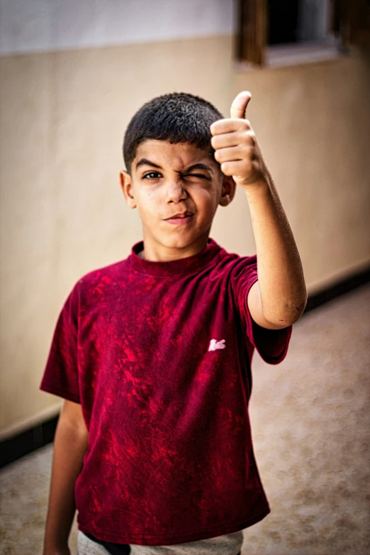 a boy in a red shirt holds a peace sign