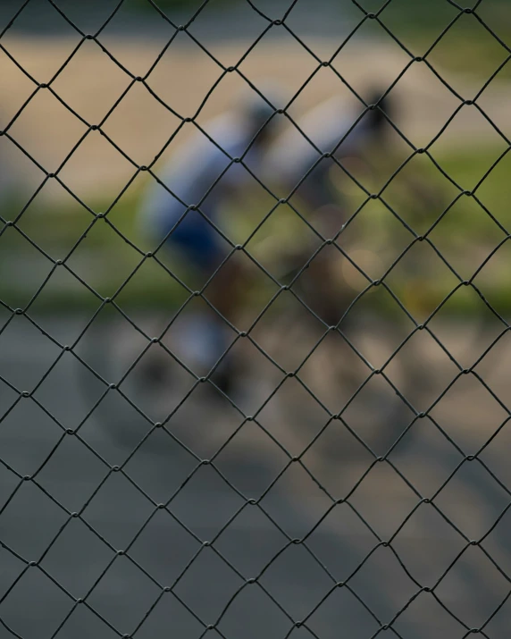 a blurry po of a person on a bike through a fence