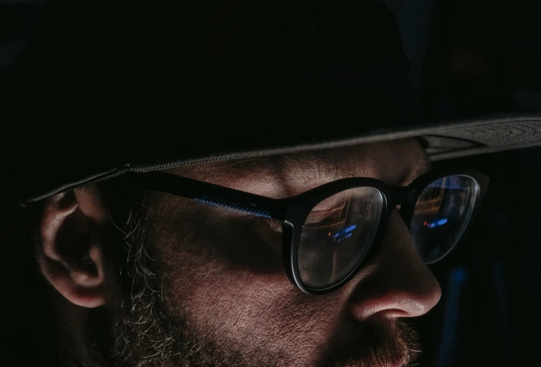 a man in a hat and glasses staring intently