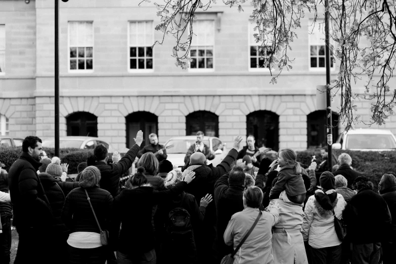 a black and white image of a crowd of people in front of a building