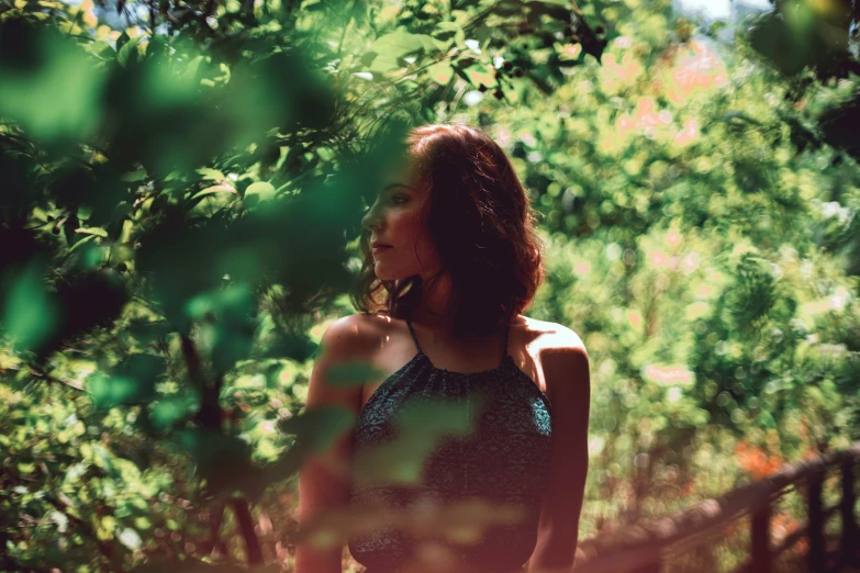 a young lady standing among leaves and trees in a forest