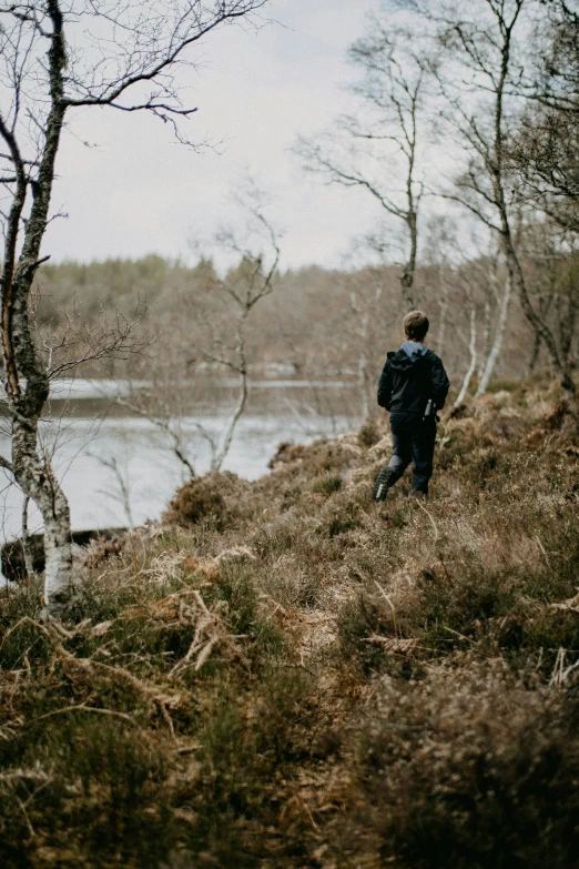 the man walks by the lake alone near some trees